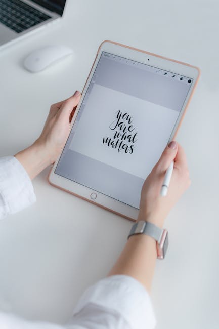A person holding a white stylus in their right hand while viewing a tablet with a rose gold case on a white desk. The tablet displays a motivational quote, 'You Are What Matters,' in black cursive font on a grey background. The left hand is resting on the desk, and a silver watch is visible on the wrist. In the background, there is a white computer mouse and part of a laptop keyboard. The surface of the desk appears clean and organized, with no visible dust or clutter, highlighting an environment suitable for professional cleaning and maintenance like those offered by Cleaners W9. The scene emphasizes a tidy, well-maintained workspace, relevant to discussions on surface cleaning, hygiene, and deep cleaning services.