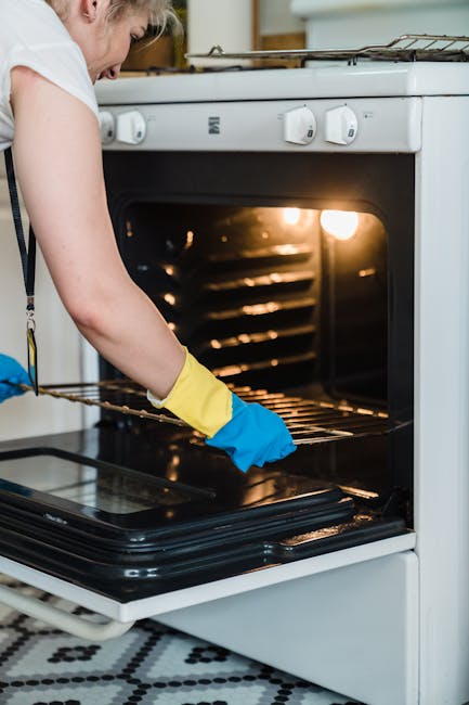 Close-up view of a stainless steel oven with a control panel featuring buttons for various functions and an illuminated digital display, situated within a kitchen. The oven door is closed, and the surface appears free of dust and grease, indicating a recent deep cleaning or sanitisation. In the background, part of a matching stainless steel microwave or another kitchen appliance is visible, along with a wooden countertop. The lighting highlights the shiny, reflective surfaces, emphasizing cleanliness and maintenance in a domestic setting, as provided by Cleaners W9's Warwick Avenue oven cleaning services in Maida Vale W9.